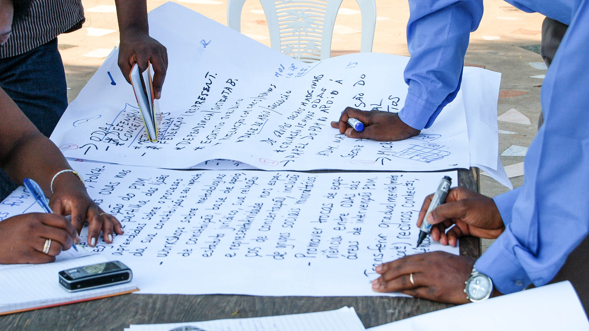 Development workers leaning over a table and collaborating on a presentation document.
