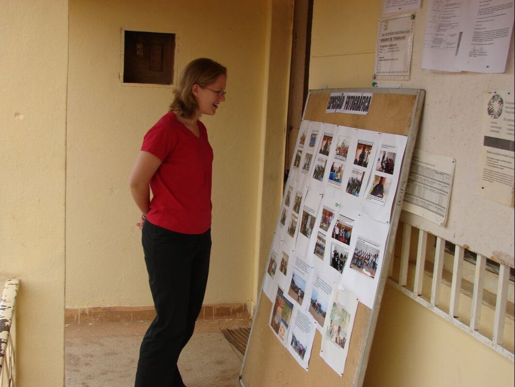 A woman looks at a board of photographs of development project work in an office.
