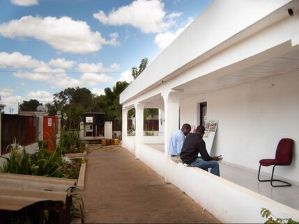 Two men sitting an a veranda having a conversation.
