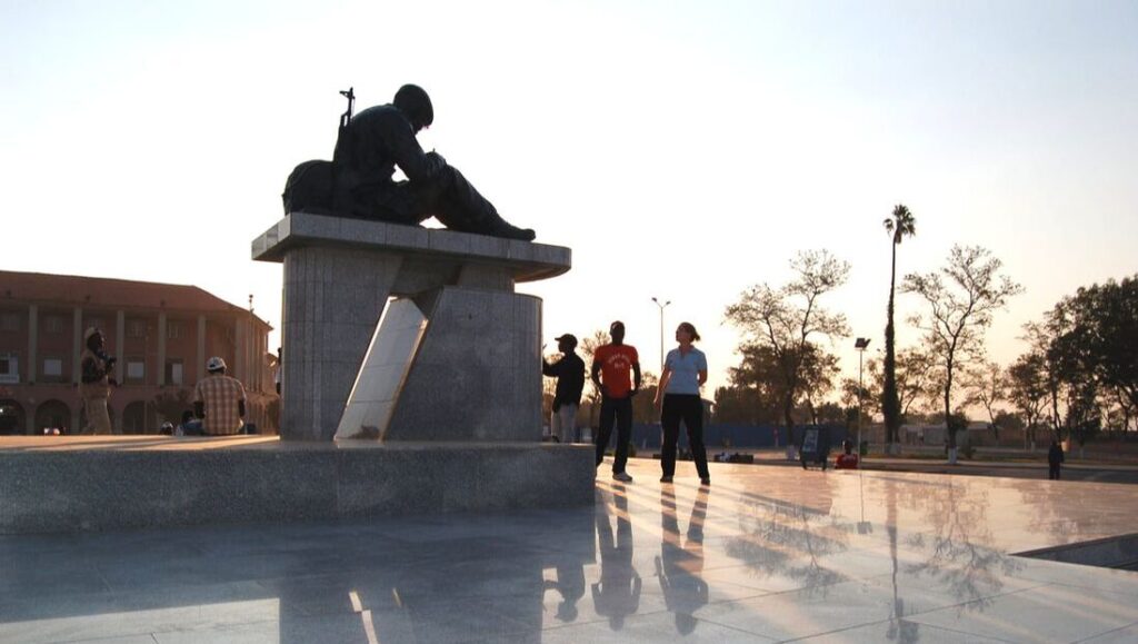 People looking at a monument of a soldier writing poetry.