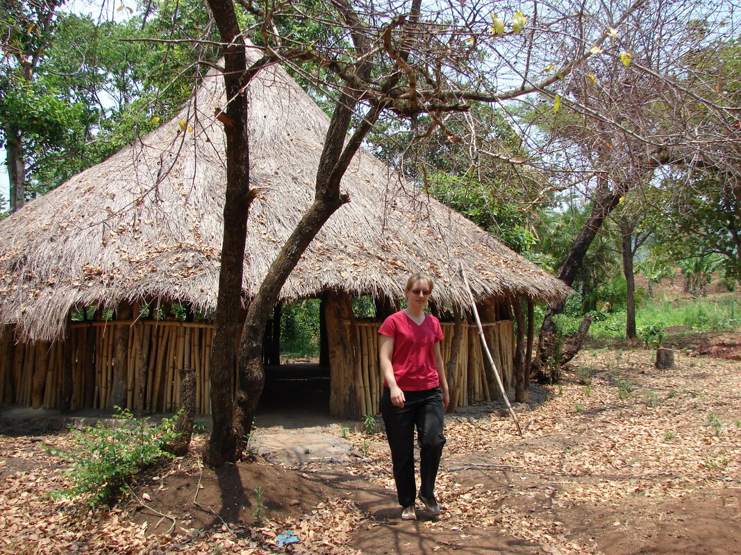 Women walking away from a communal meeting building in a forrest.