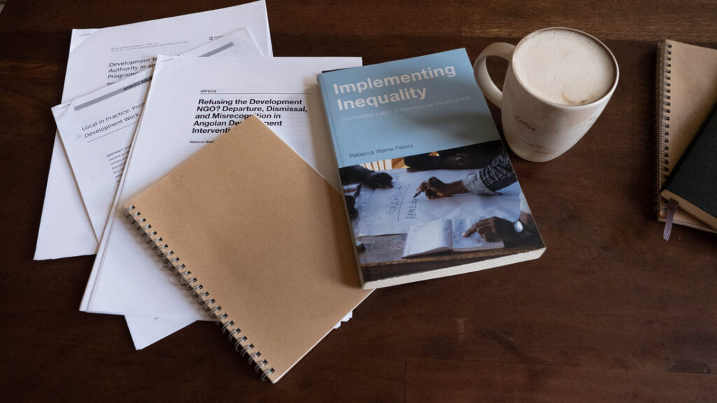 Books and papers on a table next to a coffee cup.